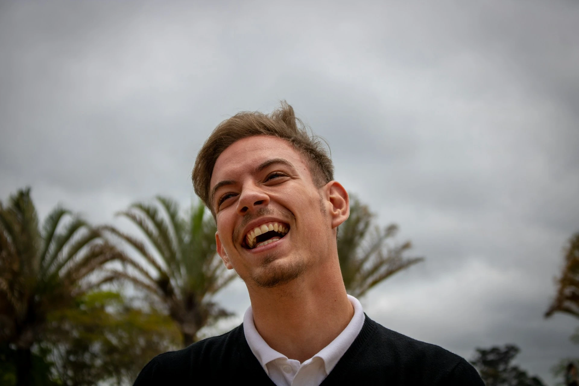 Hombre joven riendo al aire libre, bajo un cielo despejado