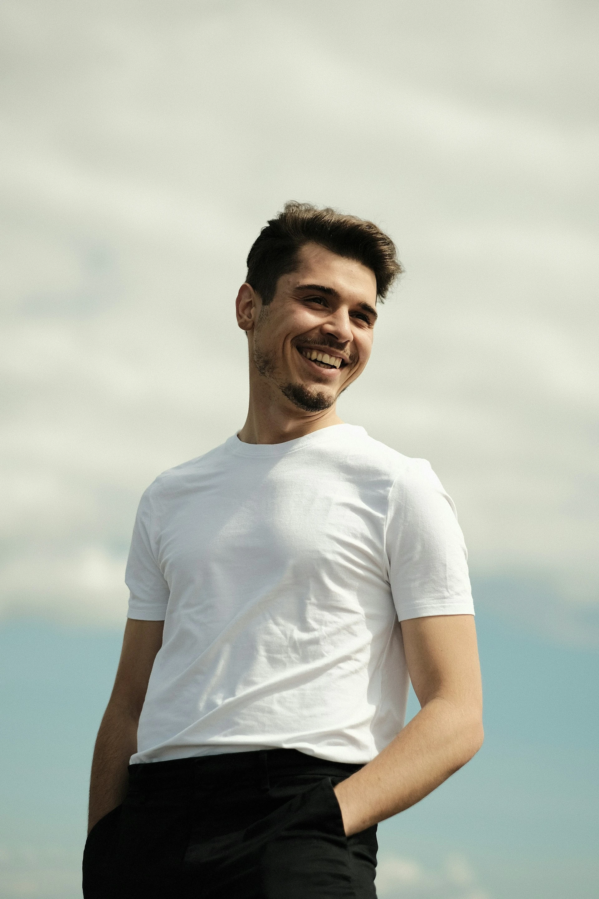 Hombre joven sonriendo al aire libre, con cielo de fondo